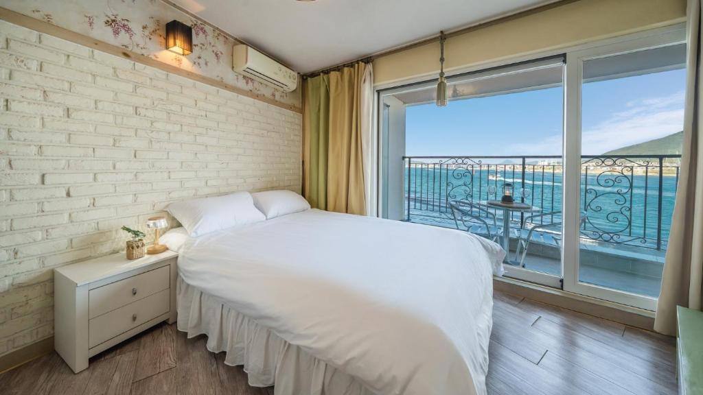 a bedroom with a white bed and a large window at tongyeong haegando pension in Tongyeong