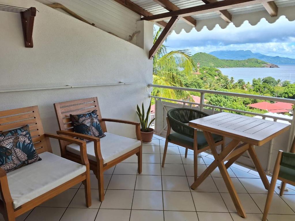 a balcony with chairs and a table and a view of the ocean at Petite Anse in Terre-de-Haut