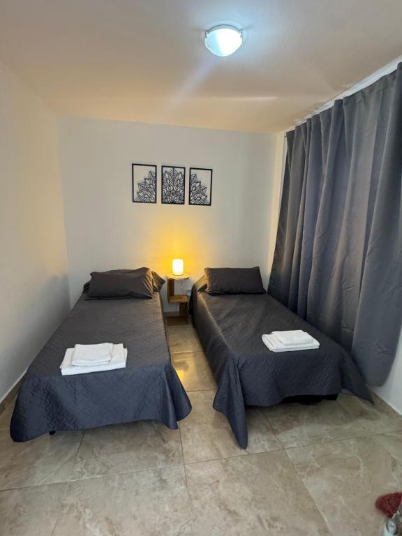 two beds sitting in a room with curtains at Apart Boulevard in Vuelta del Paraguayo