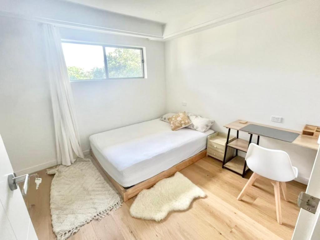 een kleine witte slaapkamer met een bed en een bureau bij Bedroom with Ensuite Near Train Station and Airport in Revesby
