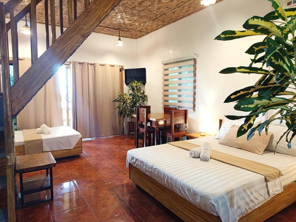 a bedroom with two beds and a table and chairs at Helmina's Villas in General Luna