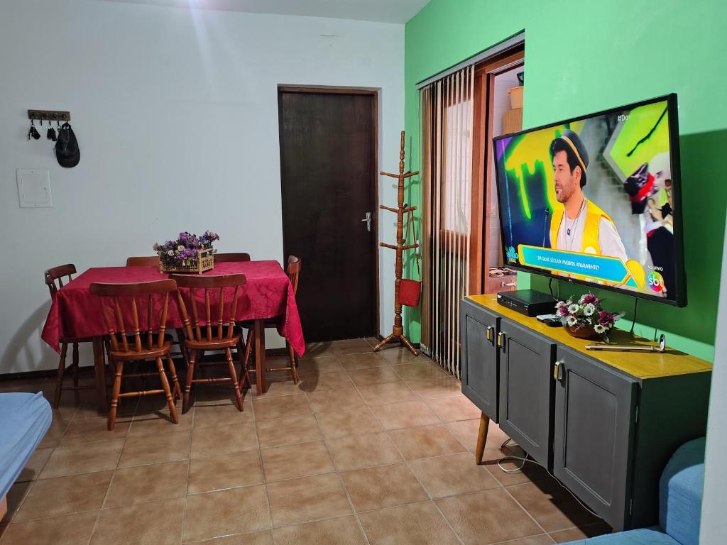 ein Wohnzimmer mit einem Tisch und einem Flachbildfernseher in der Unterkunft Aconchegante apto em Capao da Canoa in Capão da Canoa