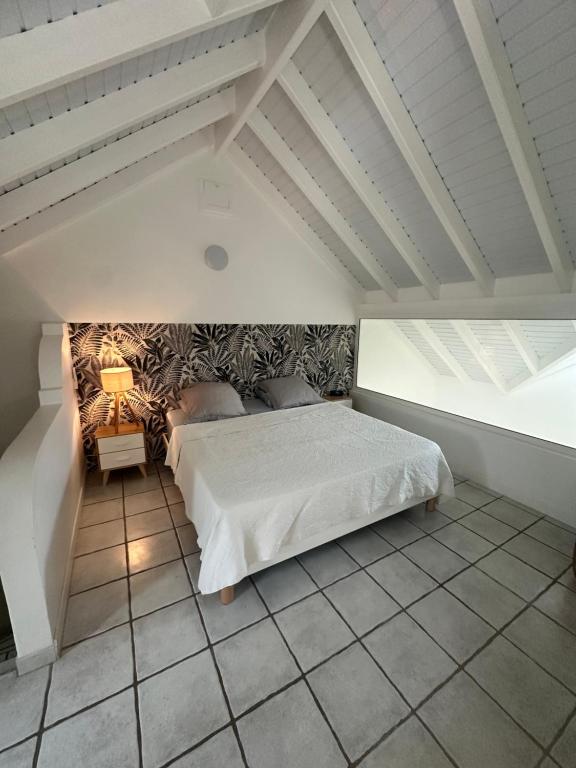 a bedroom with a white bed in a attic at Duplex Atypique et Authentique in Saint Martin