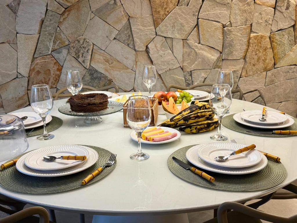 a table with plates of food and wine glasses at MHV Milagres - Naluum G04, Casa em condomínio beira mar de alto padrão, a poucos metros da Capela dos Milagres in Passo de Camarajibe