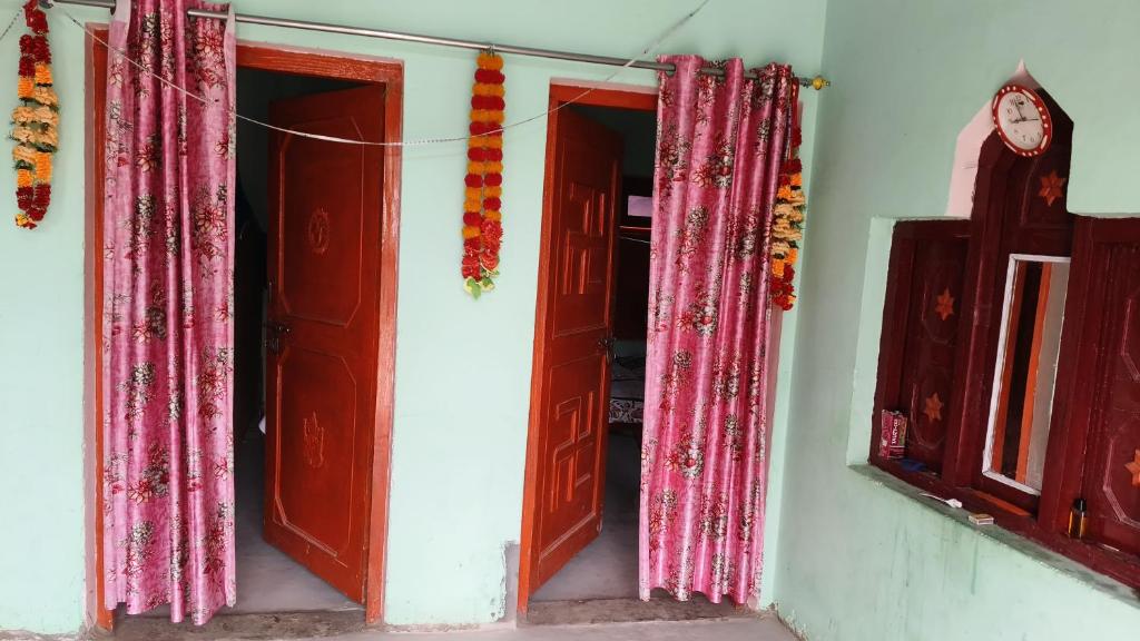 a room with two open doors and pink curtains at Radhika Home Stay 
