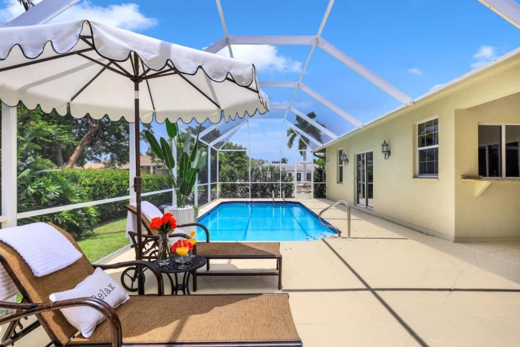 een patio met een parasol en een zwembad bij Marco Beach House l Private Pool in Marco Island