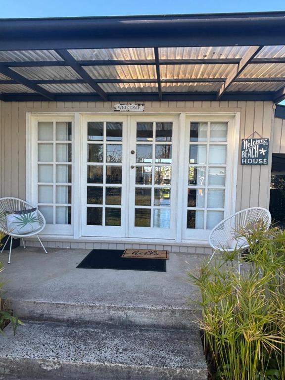a patio with two chairs and a sign in front of a building at Port Sorell Beach Shack in Port Sorell