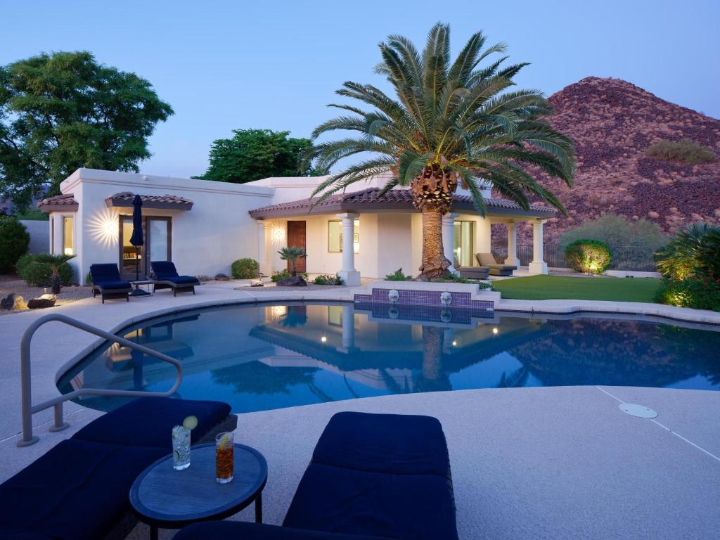 a swimming pool in front of a house with a palm tree at Luxury Mountain Estate-Pool-Spa-BBQ+Bar-Fire pit in Scottsdale