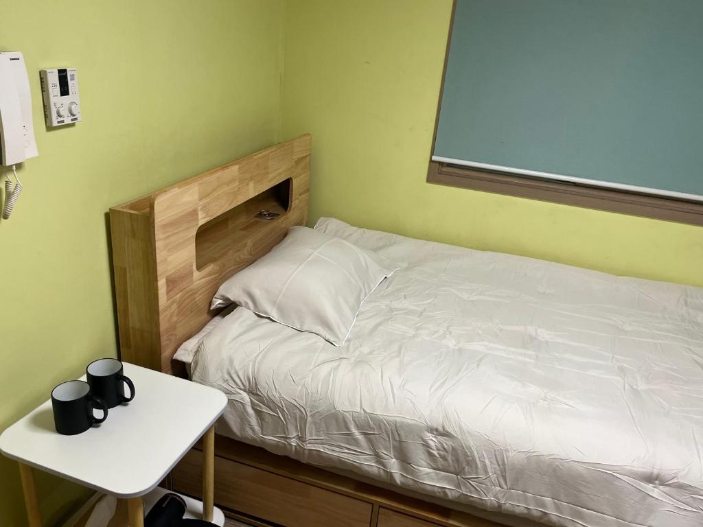Un dormitorio con una cama con una mesa y una ventana. en 전북대근처 시외버스터미널 원룸6, en Haga-ri