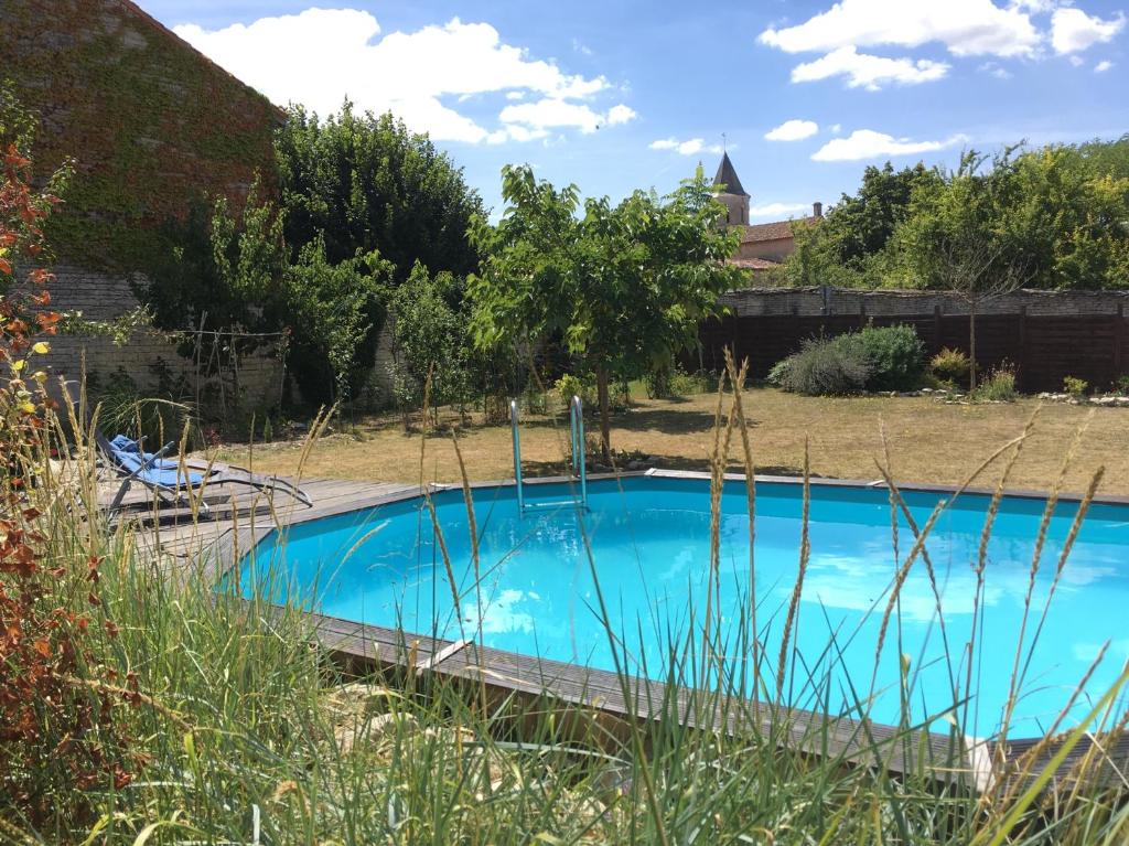 a blue swimming pool in a yard with tall grass at Le Grenier 1 Rue Verte Tusson 16140 France in Tusson