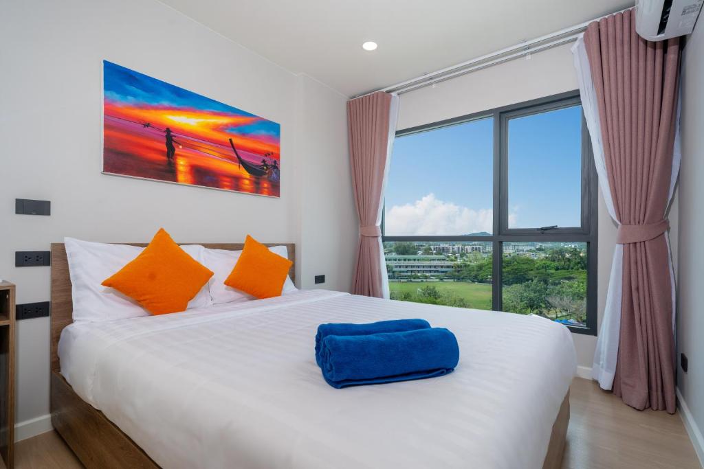 a bedroom with a large bed with a large window at Space Cherngtalay Condo in Elegant Bang Tao in Ban Thalat Choeng Thale