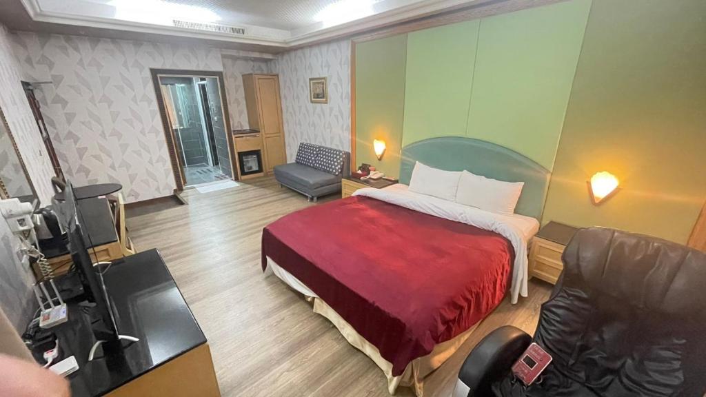 高雄花乡旅馆連鎖-凤山店的卧室里有一张床，上面铺着一条红毯子