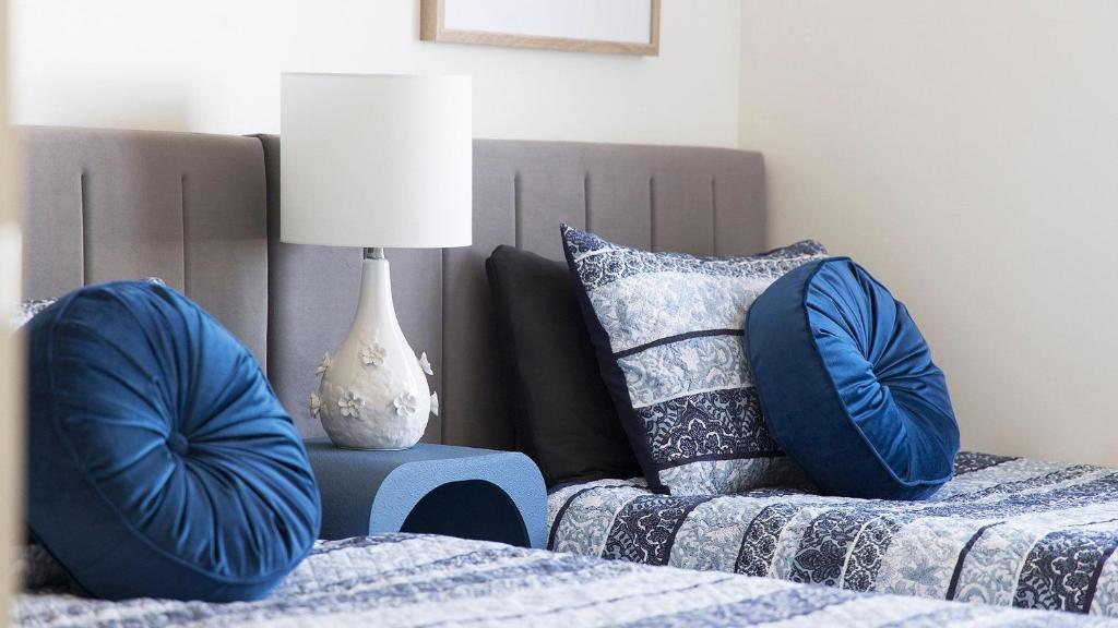 1 dormitorio con 1 cama con almohadas azules y lámpara en 4-102 Magnus Street, en Nelson Bay