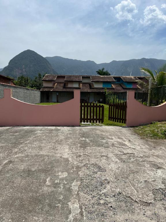 ein Haus mit einem Zaun und Bergen im Hintergrund in der Unterkunft Sarau's Beach House Boracéia in Boracéia
