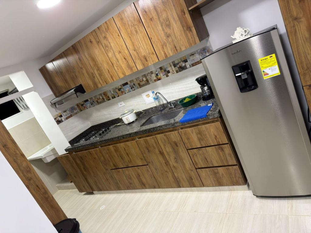 a kitchen with a stainless steel refrigerator and wooden cabinets at apartamento M&C in San Gil
