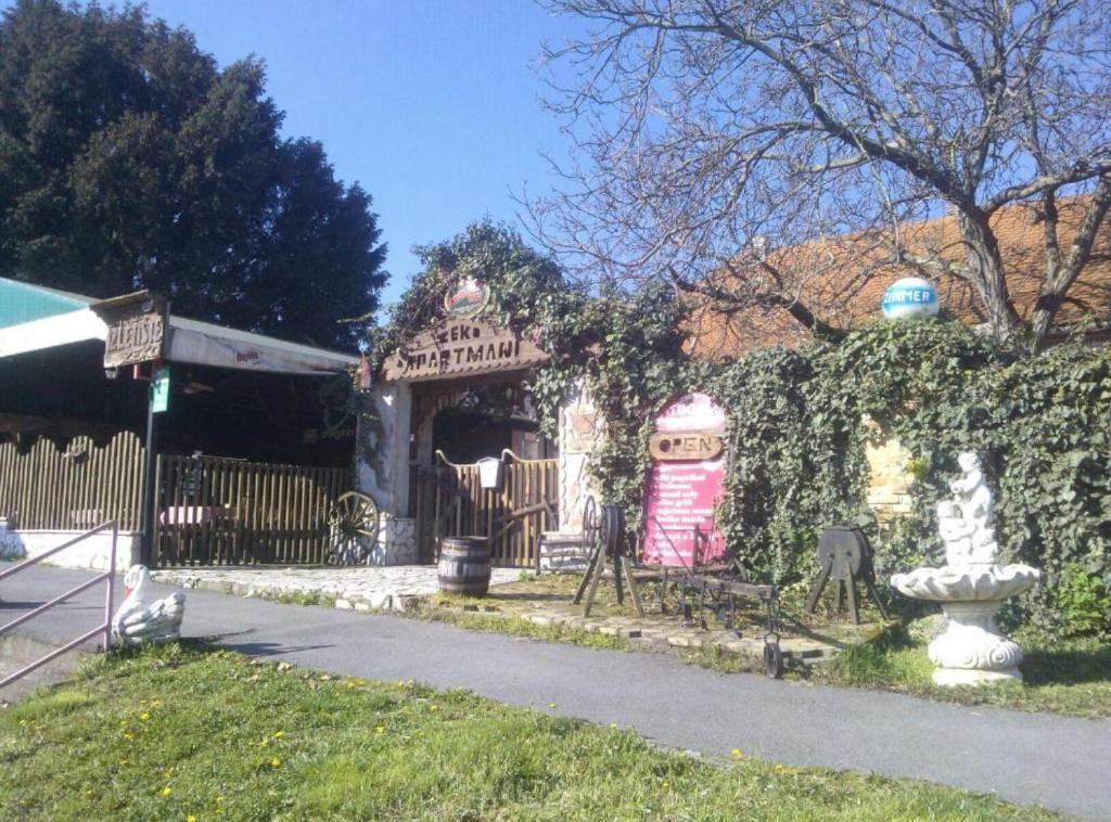 a house with a fence and a fountain in a yard at Rooms Zeko in Aljmaš