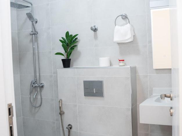 a bathroom with a shower and a potted plant at Lateen Chalet - شاليه لتين in Nizwa