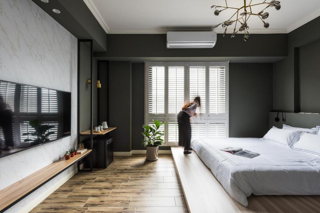 a woman looking out the window in a bedroom at 太太的小公館 入住須滿13歲以上 in Taitung City