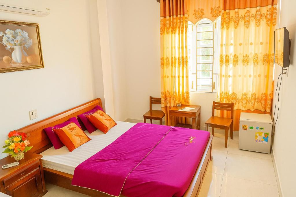 a bedroom with a bed with pink sheets and a window at Gia Hoang Hotel in Quy Nhon