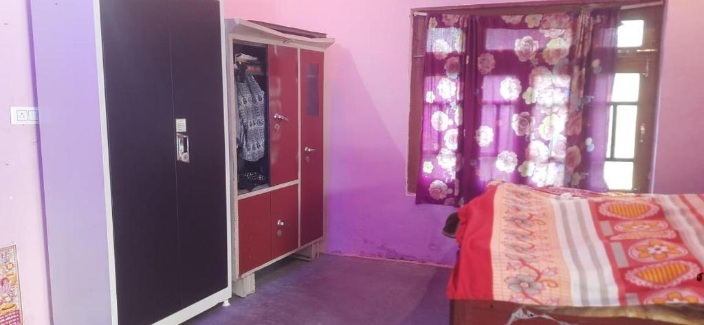 um quarto com paredes roxas, uma cama e um espelho em Kamla Tharu Home Stay 