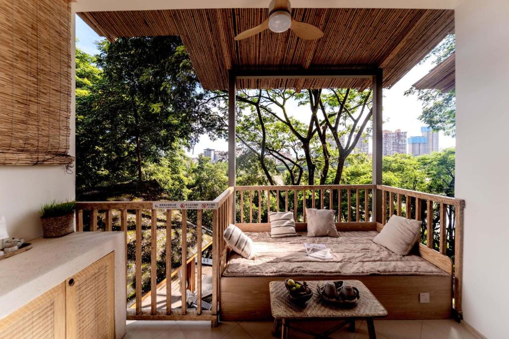 a bed on a balcony with a large window at Wanan Tinglan Wild Luxury Resort Designer Hotel in Jinghong