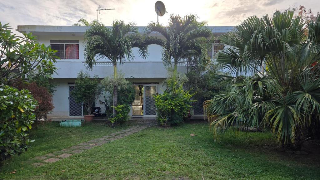 a house with palm trees in front of it at La Maison Plage et Sunset in Paeau