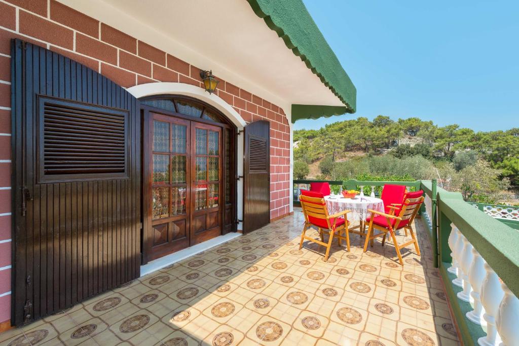a patio with red chairs and a table on a balcony at Villa Agia Galini in Archangelos