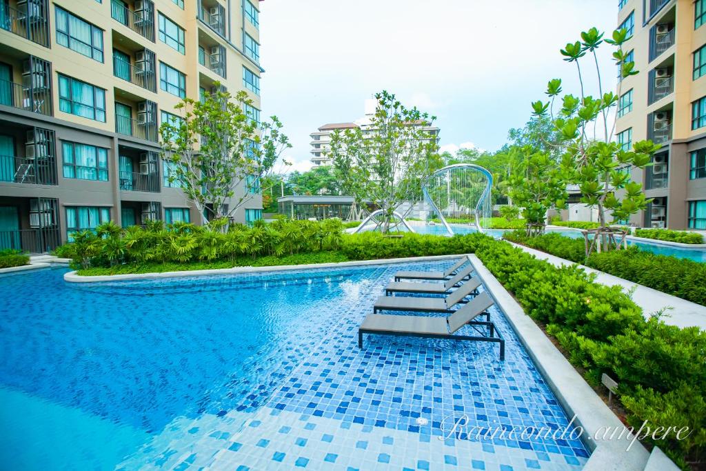 a swimming pool with a bench in front of some buildings at Raincondo Ampere in Cha Am