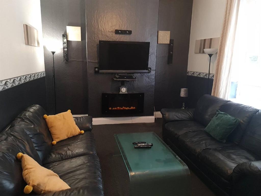 a living room with two leather couches and a fireplace at Stags Hens Contractors Longstay in Town Moor