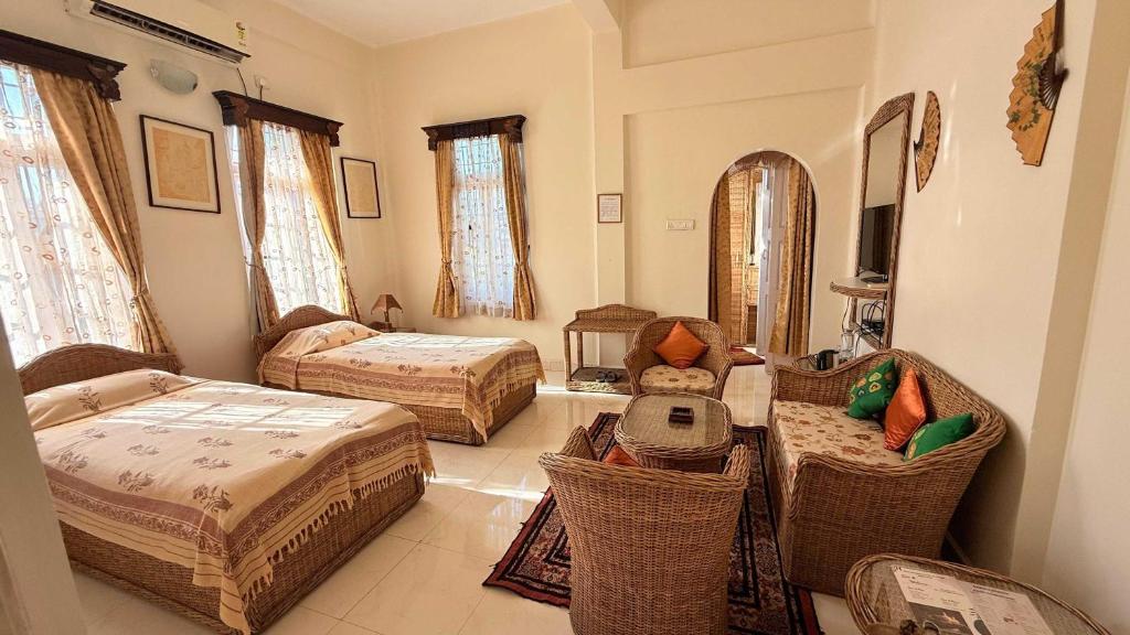 Cette chambre comprend 2 lits et des chaises. dans l'établissement Hotel O Baruah Bhavan By Axom Inn Heritage, à Guwahati