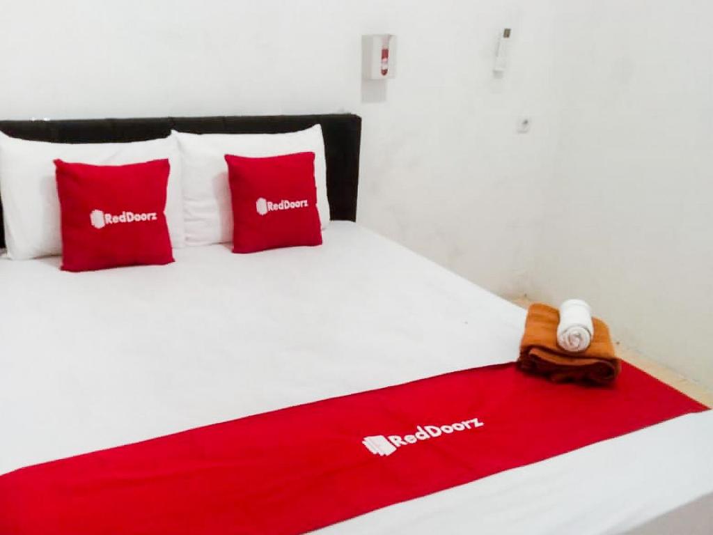 a bed with two red pillows and a red blanket at RedDoorz near Juwata 3 Airport Tarakan in Karanganyar