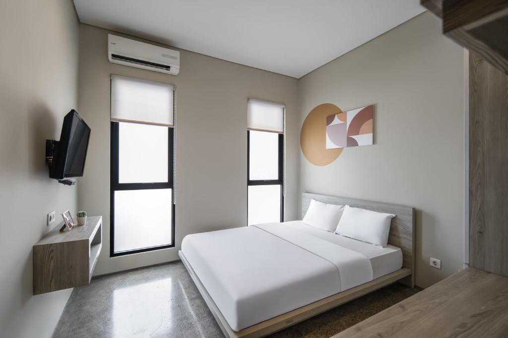 a bedroom with a white bed and two windows at Cove Heritage in Binong