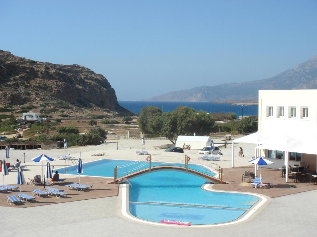a large swimming pool with chairs and umbrellas next to a building at Royal Beach Hotel in Arkasa