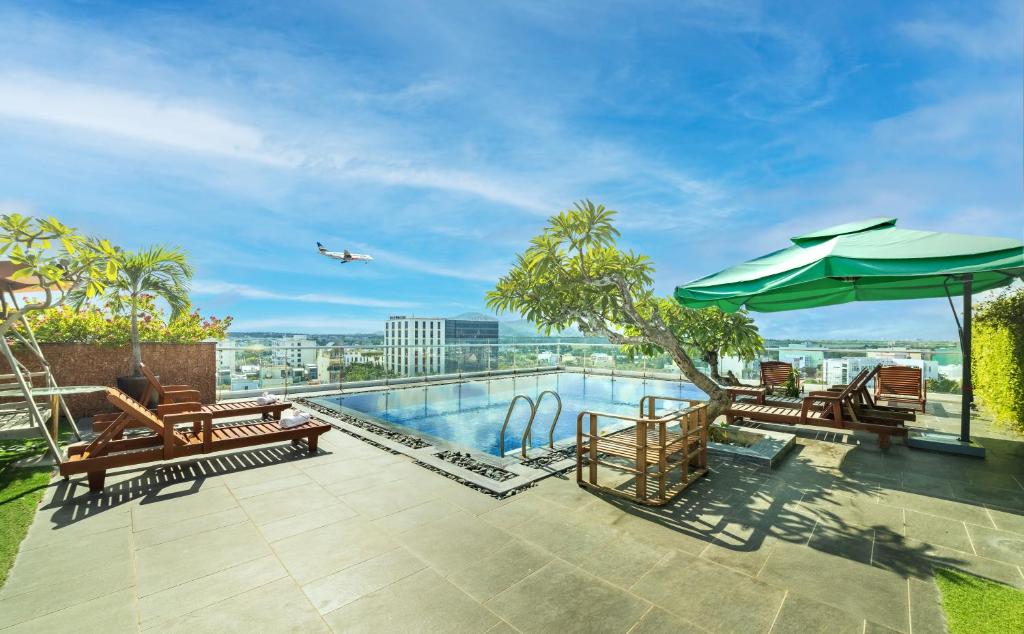 a pool with benches and an umbrella and an airplane at MTR Apartment & Hotel in Da Nang