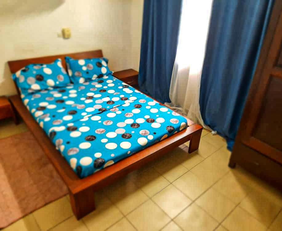 コトヌーにあるEntré personnelle à fidjrosseの青い掛け布団と青いカーテンが付いたベッド