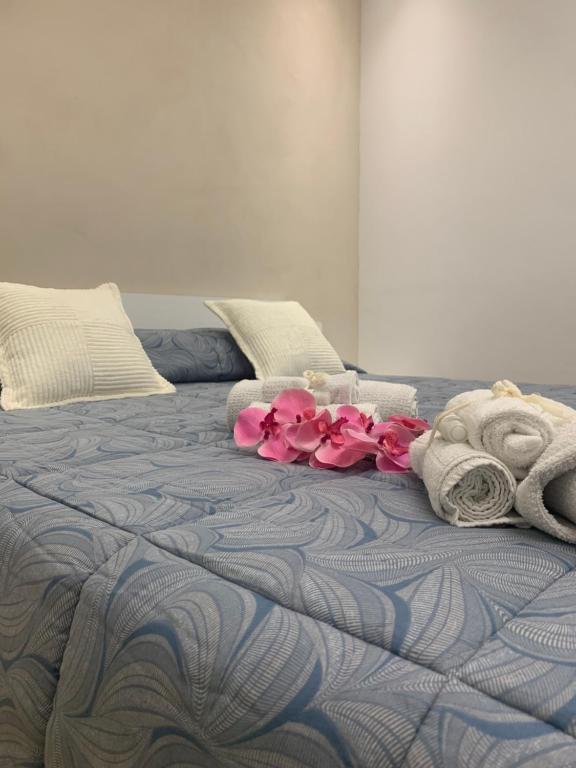 Una cama con toallas y flores rosas. en Appartamento centro Elpidio Blu, en Porto SantʼElpidio