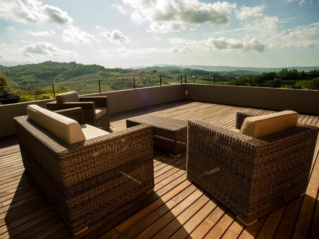 a balcony with wicker chairs and tables on a deck at Apartment Oton Reya in Dobrovo