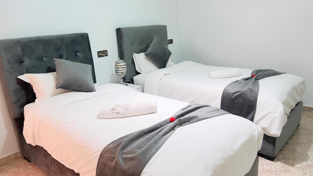 two beds in a room with white and gray at Magnifique maison famiiale moderne spacieuse de 150 m Avec de 3 chambres ,confortables et d un grand salon et terrasse, Idealement situee a 9 min du centre-ville elle se trouve à proximite de la route principale menant a l aeroport Berkane et Saidia in Oujda