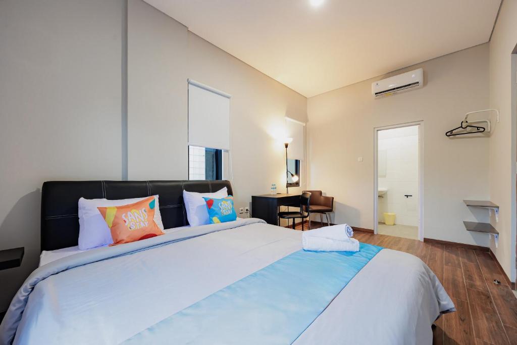 a bedroom with a large bed with orange and blue pillows at Sans Stay Bintaro in Pondoklang