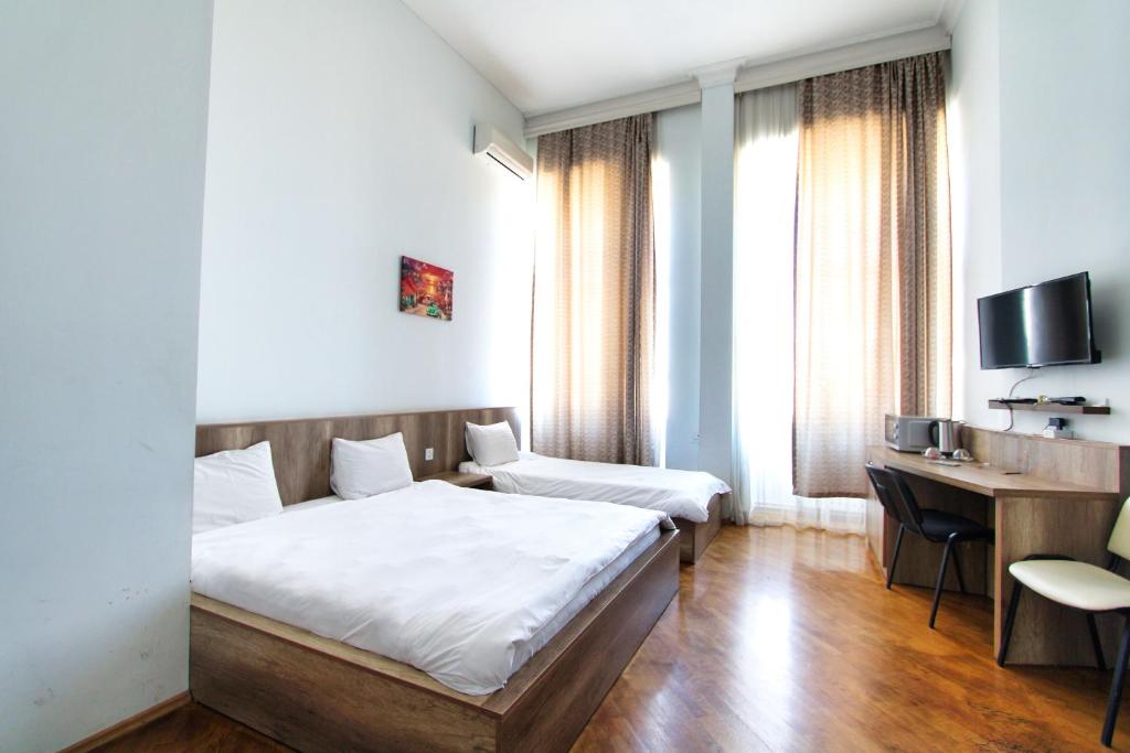 a bedroom with a bed and a desk and a television at Liman Apartment Nz in Baku