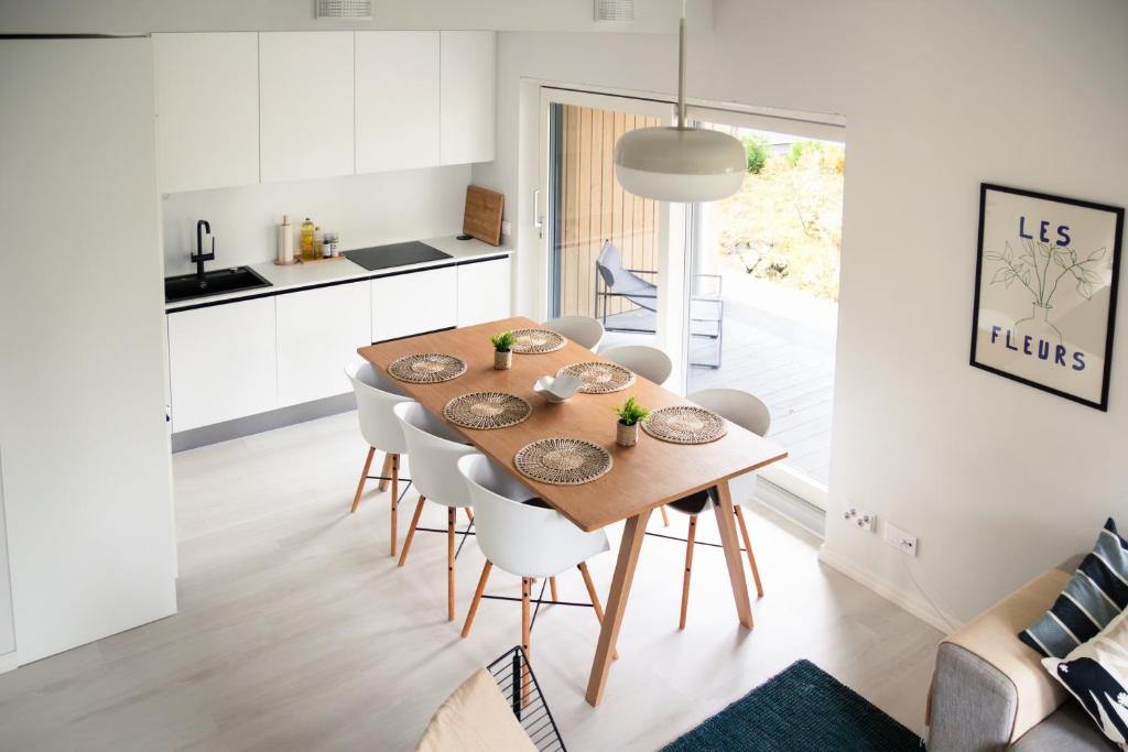 a kitchen and dining room with a wooden table and chairs at Brand new house with four bedrooms, parking, sauna, patio in Vantaa