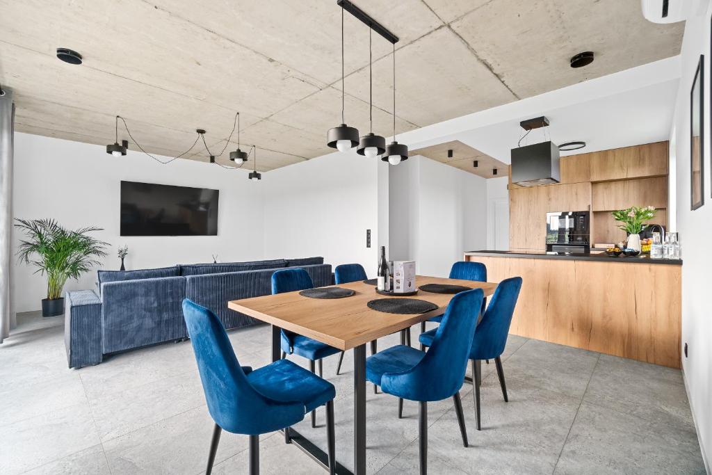 a dining room with a wooden table and blue chairs at Jack Apartments- Kamień Śląski in Kamień Śląski