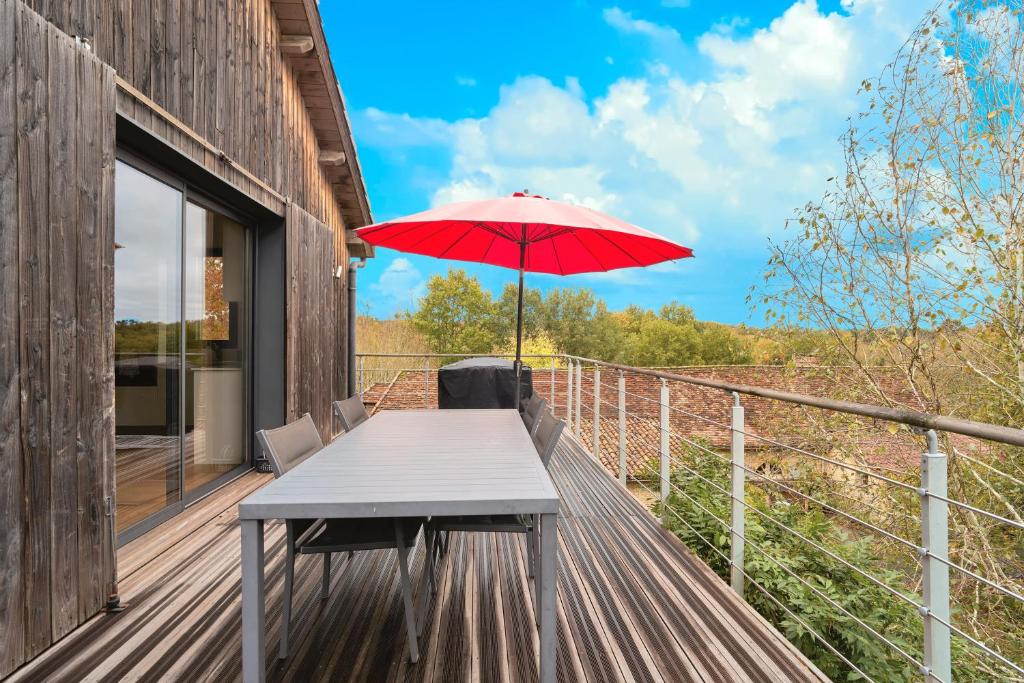 a table with a red umbrella on a deck at Loft Ôrizon - Domaine De L'ô in Bellacaud