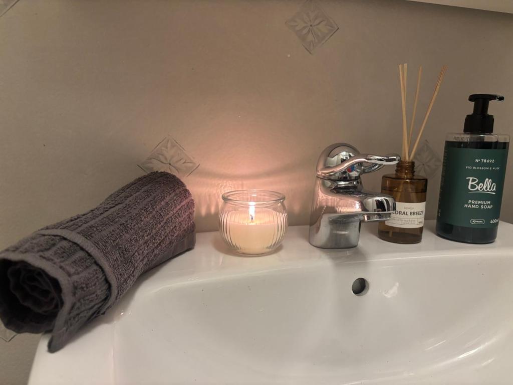 een wastafel in de badkamer met een kaars en een handdoek bij Cozy apartment in Åmål