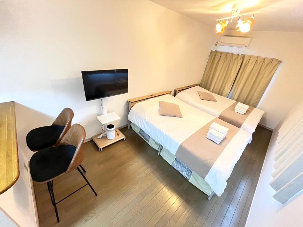 a bedroom with a bed and a chair and a television at Camelot House in Fukuoka