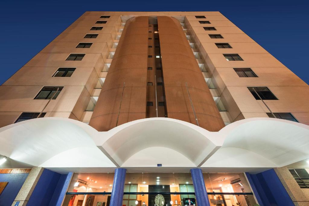 a tall building with blue columns in front of it at Hotel Executive Arrey in Teresina