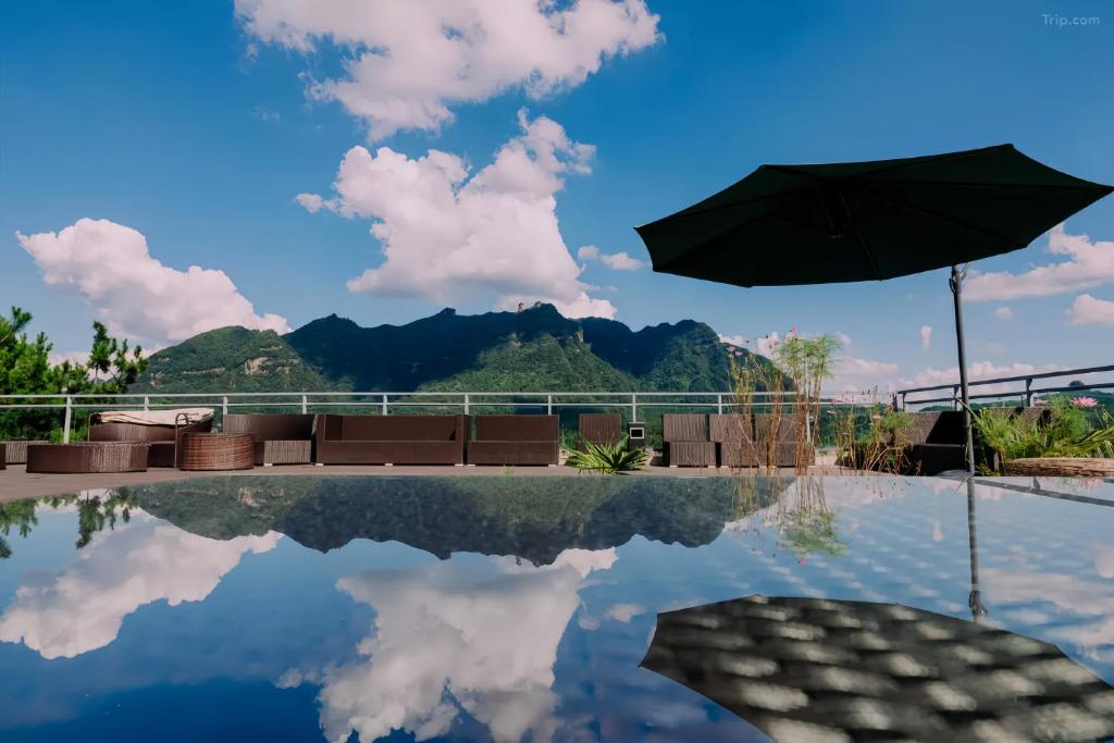a pool with an umbrella and mountains in the background at Azure Peaks-English Services-At National Forest Park with Free Shuttle in Zhangjiajie