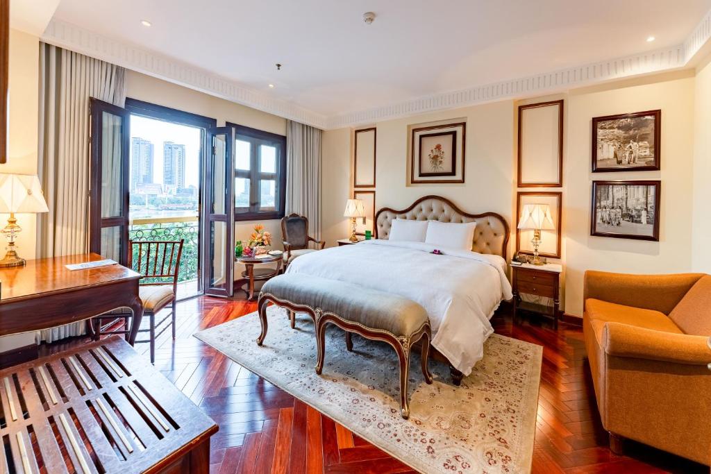 a bedroom with a bed and a living room at Hotel Majestic Saigon in Ho Chi Minh City
