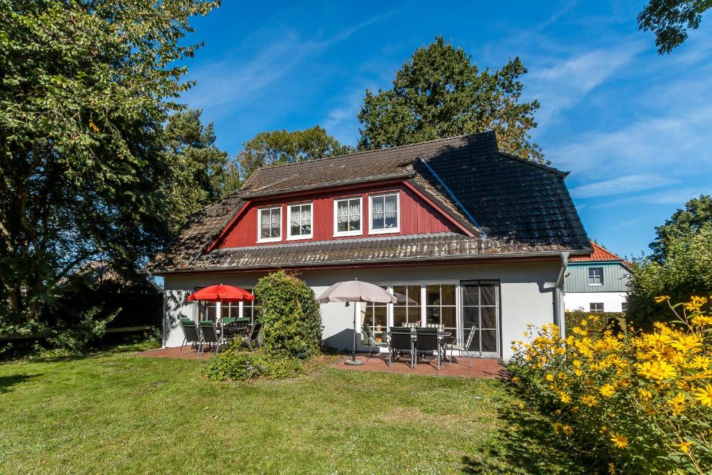 a red and white house with chairs and umbrellas at Jagdhaus Prerowstrom in Jagdhaus