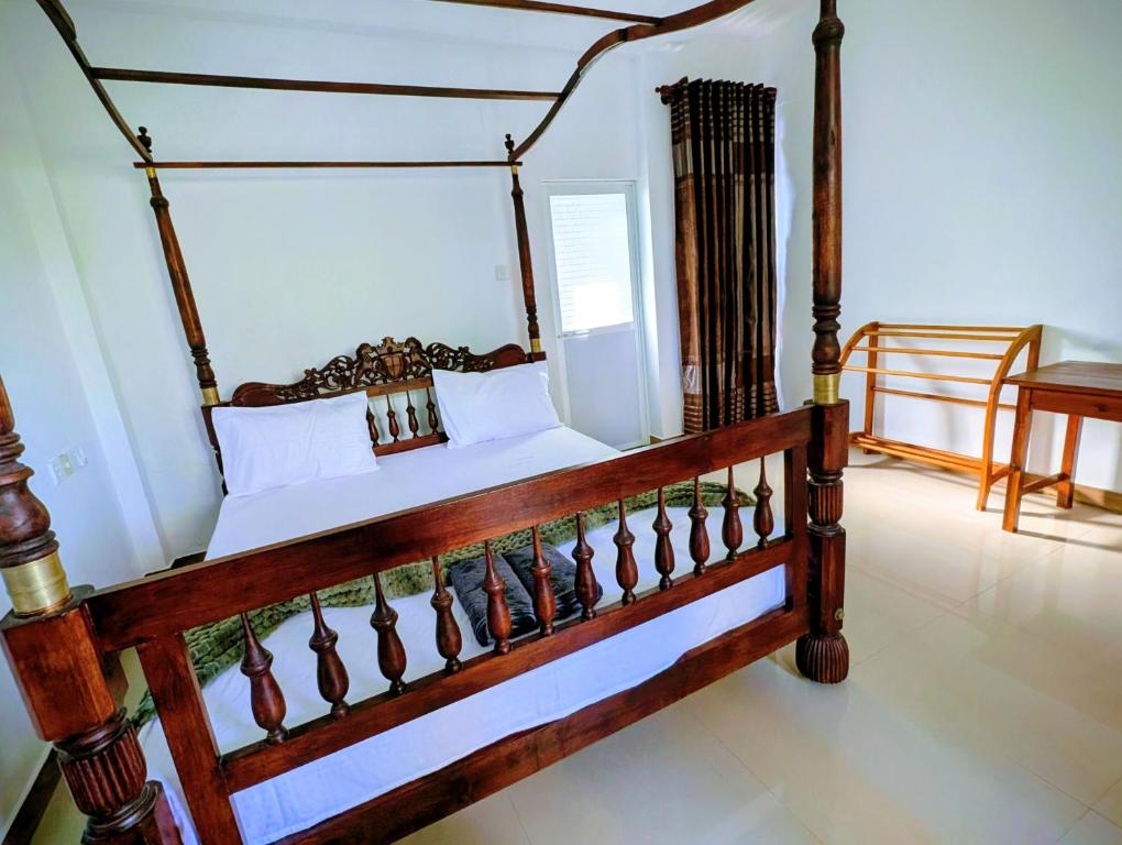 a bedroom with a wooden canopy bed with white pillows at Costels Coconut hill in Mirissa